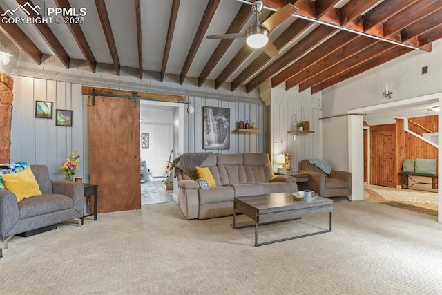 carpeted living area with a barn door, wood walls, ceiling fan, and beam ceiling