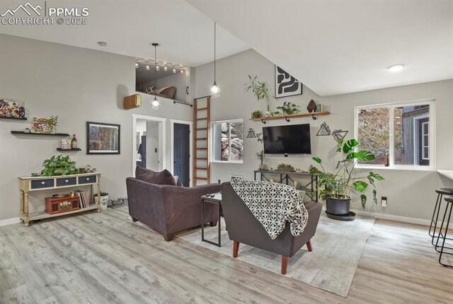 living room featuring wood finished floors, baseboards, and high vaulted ceiling