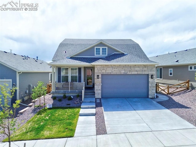 5932 Torrisdale Vw, Colorado Springs, CO 80927 - view of front facade with covered porch, a shingled roof, an attached garage, stone siding, and concrete driveway