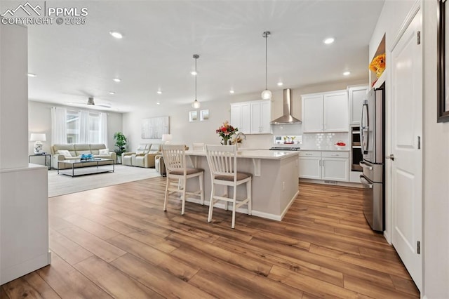 5932 Torrisdale Vw, Colorado Springs, CO 80927 - kitchen with wall chimney range hood, stainless steel fridge with ice dispenser, light wood-type flooring, white cabinets, and recessed lighting