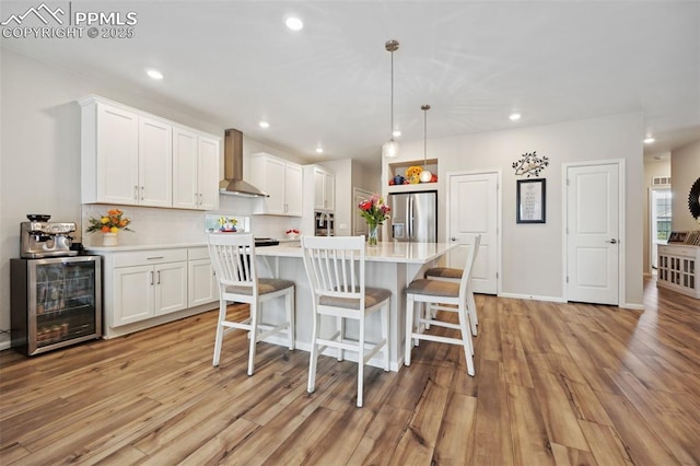 5932 Torrisdale Vw, Colorado Springs, CO 80927 - kitchen with stainless steel refrigerator with ice dispenser, wall chimney exhaust hood, beverage cooler, light wood-type flooring, and light countertops