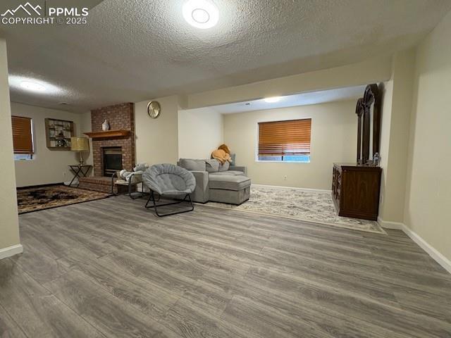 905 Hubbell Dr, Colorado Springs, CO 80911 - living area with a textured ceiling, wood finished floors, baseboards, and a brick fireplace