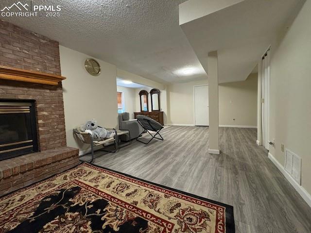 905 Hubbell Dr, Colorado Springs, CO 80911 - living area featuring wood finished floors, a fireplace, baseboards, and a textured ceiling