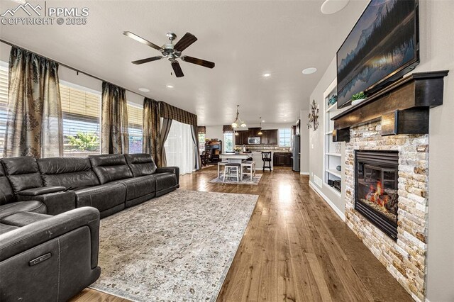 10282 Mt Lincoln Dr, Peyton, CO 80831 - living area with a ceiling fan, wood finished floors, recessed lighting, a stone fireplace, and built in shelves