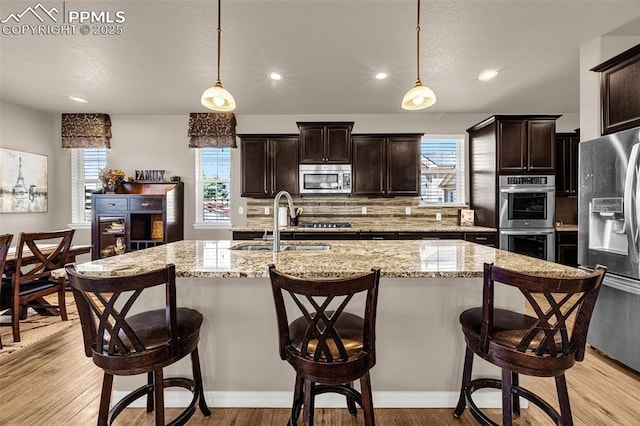 10282 Mt Lincoln Dr, Peyton, CO 80831 - kitchen with a sink, stainless steel appliances, backsplash, light wood-style floors, and dark brown cabinets