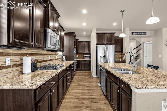 10282 Mt Lincoln Dr, Peyton, CO 80831 - kitchen featuring a sink, stainless steel appliances, light wood-style flooring, dark brown cabinetry, and decorative backsplash