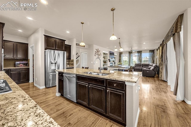 10282 Mt Lincoln Dr, Peyton, CO 80831 - kitchen featuring stainless steel appliances, a sink, light wood-style floors, dark brown cabinetry, and open floor plan