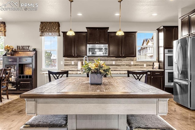 10282 Mt Lincoln Dr, Peyton, CO 80831 - kitchen featuring stainless steel appliances, dark brown cabinets, backsplash, light wood-type flooring, and recessed lighting