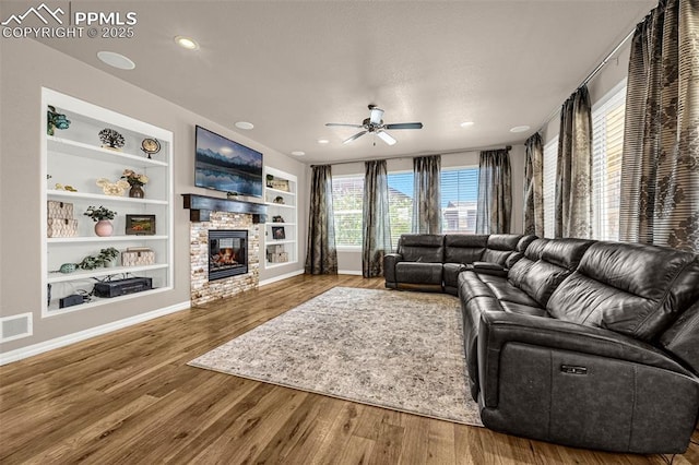 10282 Mt Lincoln Dr, Peyton, CO 80831 - living room with ceiling fan, built in shelves, wood finished floors, a stone fireplace, and baseboards