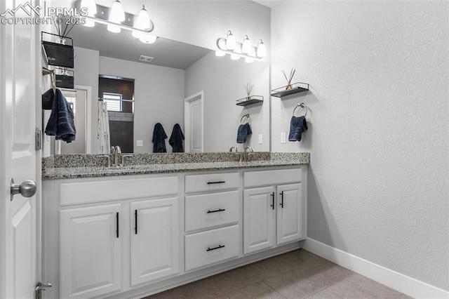 8674 Tranquil Knoll Ln, Colorado Springs, CO 80927 - full bathroom with double vanity, baseboards, tile patterned floors, and a textured wall