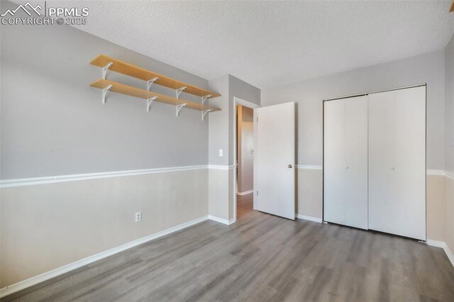 1223 Soaring Eagle Dr, Colorado Springs, CO 80915 - unfurnished bedroom featuring wood finished floors, a textured ceiling, baseboards, and a closet
