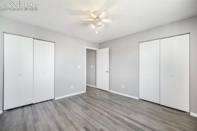 1223 Soaring Eagle Dr, Colorado Springs, CO 80915 - unfurnished bedroom featuring two closets, wood finished floors, baseboards, and a ceiling fan