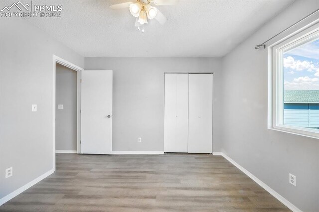 1223 Soaring Eagle Dr, Colorado Springs, CO 80915 - unfurnished bedroom featuring a textured ceiling, wood finished floors, a closet, ceiling fan, and baseboards