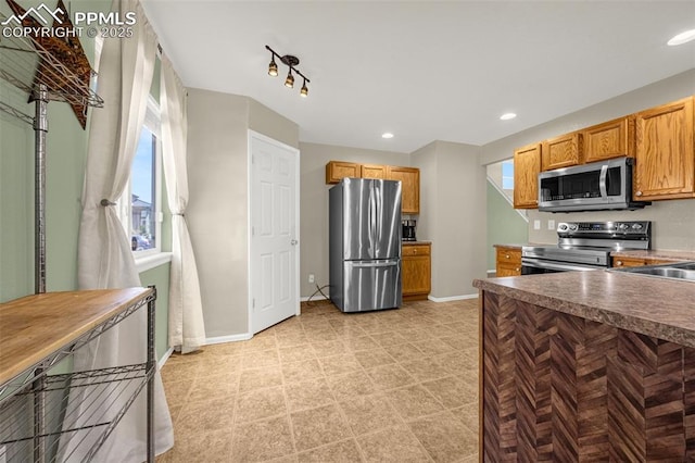 8290 Meadowcrest Dr, Fountain, CO 80817 - kitchen featuring stainless steel appliances, baseboards, recessed lighting, brown cabinetry, and a sink