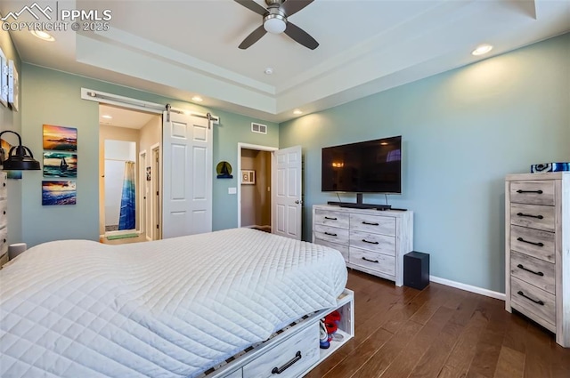 7225 Horizon Wood Ln, Colorado Springs, CO 80927 - bedroom featuring a barn door, dark wood-type flooring, a tray ceiling, baseboards, and recessed lighting