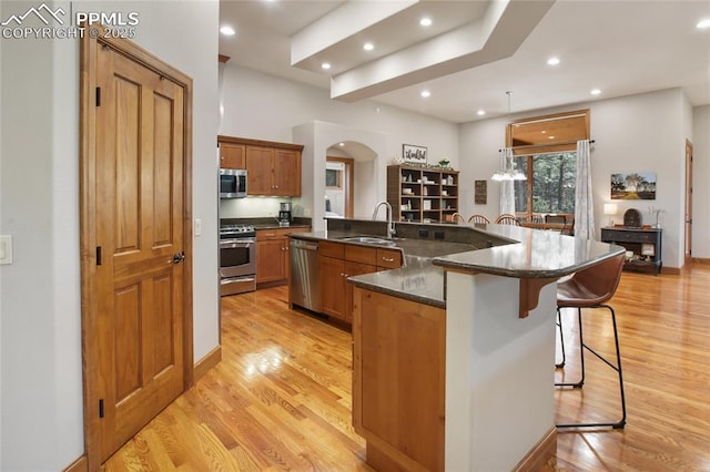 1230 Cottontail Trl, Woodland Park, CO 80863 - kitchen with stainless steel appliances, arched walkways, a kitchen breakfast bar, light wood-style floors, and a sink