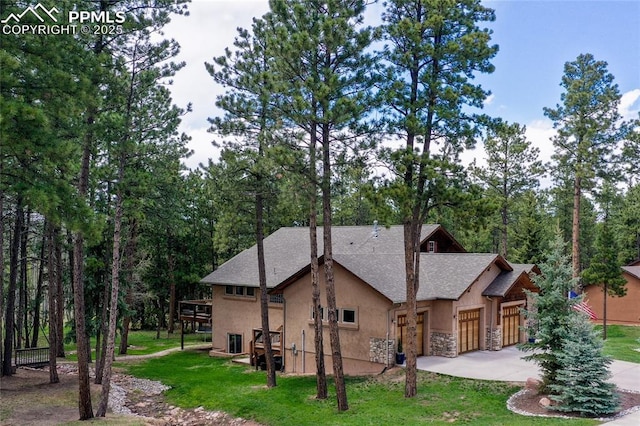 1230 Cottontail Trl, Woodland Park, CO 80863 - rear view of property with stucco siding, a garage, stone siding, concrete driveway, and a yard