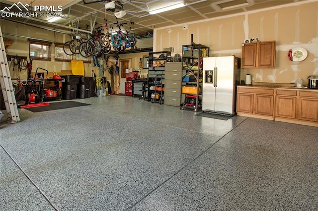 1230 Cottontail Trl, Woodland Park, CO 80863 - garage with stainless steel fridge with ice dispenser, a garage door opener, and a workshop area