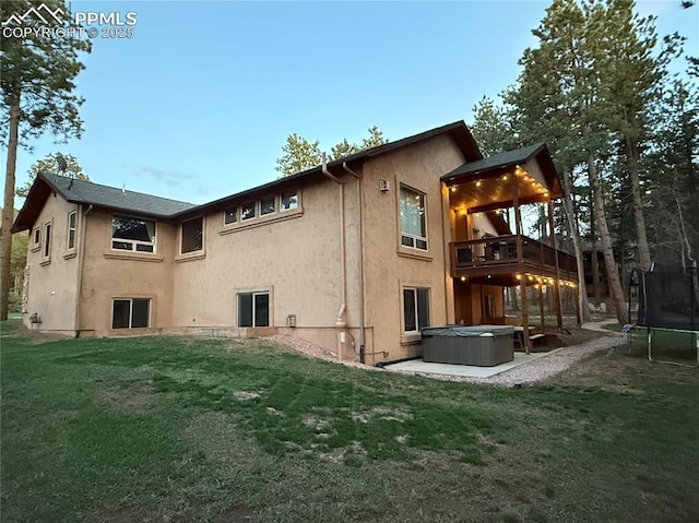1230 Cottontail Trl, Woodland Park, CO 80863 - back of property featuring a trampoline, a hot tub, stucco siding, and a yard