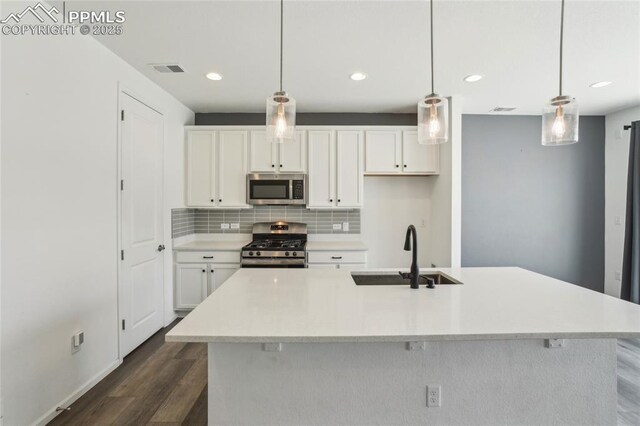 1145 Ibex Dr, Severance, CO 80550 - kitchen featuring appliances with stainless steel finishes, a sink, dark wood-type flooring, white cabinets, and tasteful backsplash
