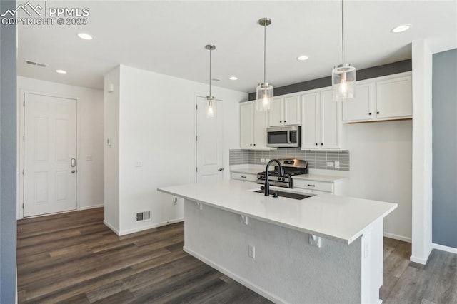 1145 Ibex Dr, Severance, CO 80550 - kitchen featuring stainless steel appliances, a sink, dark wood-style flooring, white cabinets, and decorative backsplash