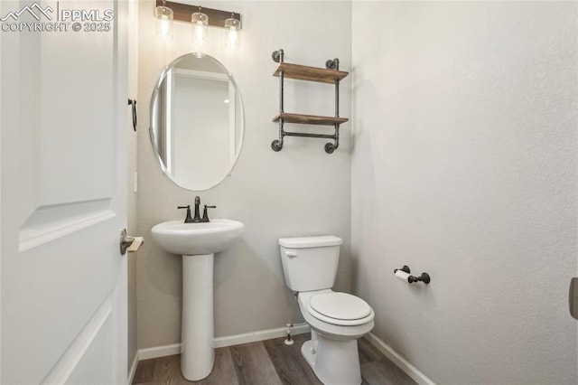 1145 Ibex Dr, Severance, CO 80550 - half bath featuring wood finished floors, toilet, baseboards, and a sink