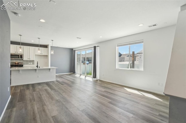 1145 Ibex Dr, Severance, CO 80550 - unfurnished living room with recessed lighting, wood finished floors, baseboards, and a sink
