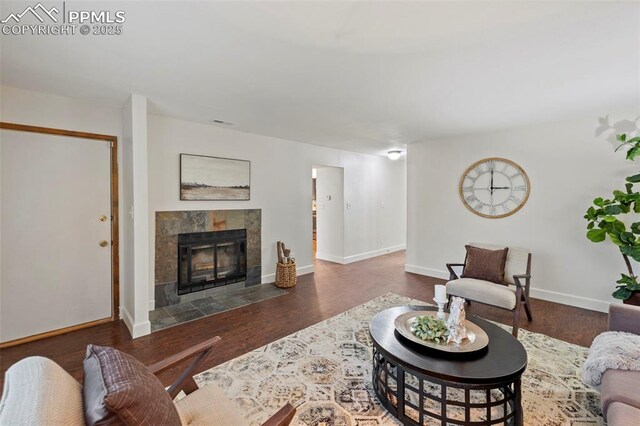6947 Gayle Lyn Ln, Colorado Springs, CO 80919 - living room with wood finished floors, a tiled fireplace, and baseboards