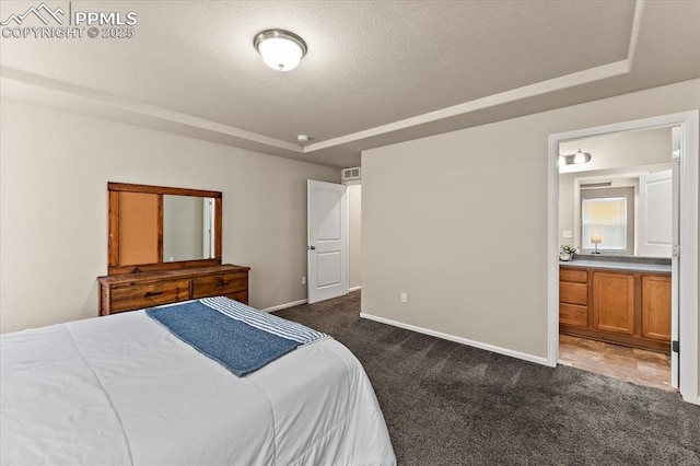 7890 Treehouse Ter, Fountain, CO 80817 - bedroom with dark carpet, a raised ceiling, ensuite bathroom, and a textured ceiling