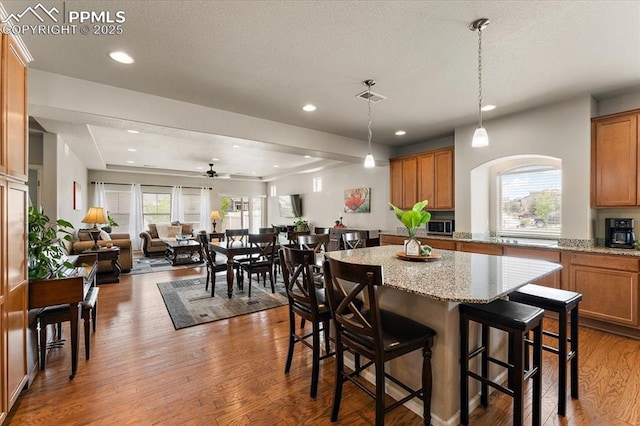 7890 Treehouse Ter, Fountain, CO 80817 - kitchen featuring brown cabinetry, wood finished floors, a kitchen island, open floor plan, and recessed lighting