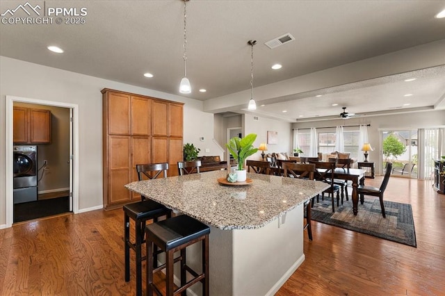 7890 Treehouse Ter, Fountain, CO 80817 - kitchen featuring washer / dryer, dark wood-style flooring, a breakfast bar, brown cabinets, and recessed lighting