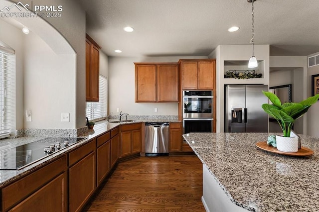 7890 Treehouse Ter, Fountain, CO 80817 - kitchen with stainless steel appliances, healthy amount of natural light, brown cabinetry, recessed lighting, and a textured ceiling