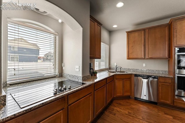 7890 Treehouse Ter, Fountain, CO 80817 - kitchen featuring appliances with stainless steel finishes, dark wood-style flooring, stone counters, brown cabinets, and recessed lighting