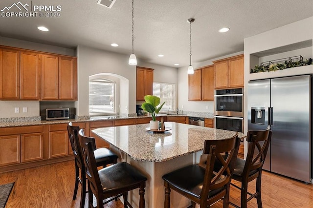 7890 Treehouse Ter, Fountain, CO 80817 - kitchen with stainless steel appliances, brown cabinetry, recessed lighting, and a kitchen bar