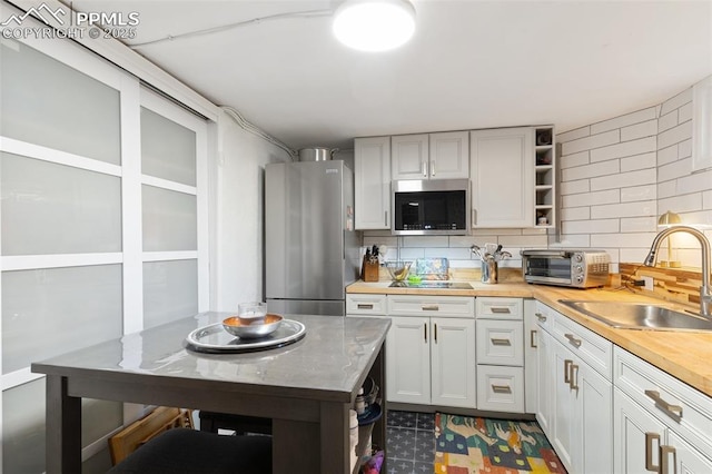 20 W Caramillo St, Colorado Springs, CO 80907 - kitchen featuring stainless steel appliances, open shelves, a sink, decorative backsplash, and butcher block counters