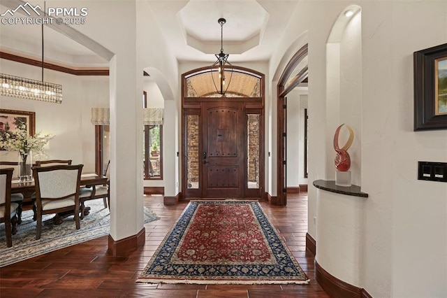 1624 Oakmoor Hts, Colorado Springs, CO 80906 - foyer entrance featuring arched walkways, dark wood-type flooring, a tray ceiling, a chandelier, and baseboards