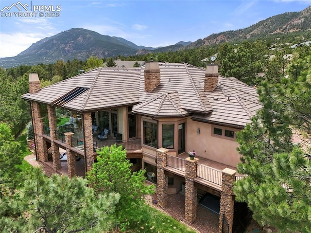 1624 Oakmoor Hts, Colorado Springs, CO 80906 - back of property featuring a chimney, stucco siding, a deck with mountain view, and a tiled roof