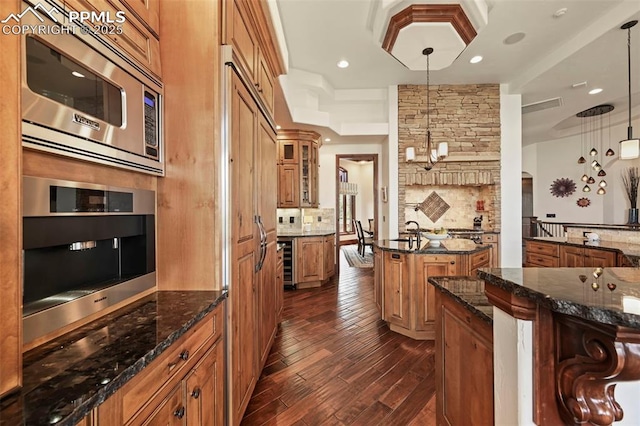 1624 Oakmoor Hts, Colorado Springs, CO 80906 - kitchen with stainless steel microwave, brown cabinets, dark wood finished floors, decorative backsplash, and arched walkways