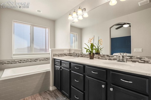 13124 Park Meadows Dr, Peyton, CO 80831 - ensuite bathroom with wood finished floors, a garden tub, double vanity, backsplash, and a ceiling fan