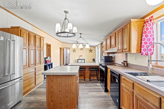 10635 Via Vaquaro Pt, Fountain, CO 80817 - kitchen featuring stainless steel appliances, under cabinet range hood, dark wood-style floors, a chandelier, and crown molding
