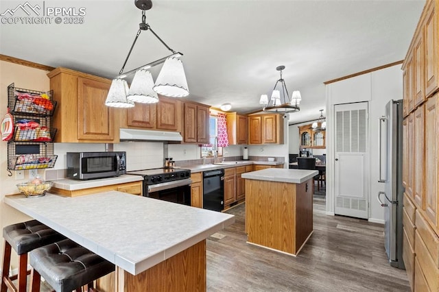 10635 Via Vaquaro Pt, Fountain, CO 80817 - kitchen with appliances with stainless steel finishes, a chandelier, under cabinet range hood, light countertops, and a peninsula