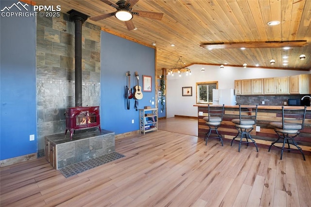 2747 County Road 61, Cripple Creek, CO 80813 - kitchen with white fridge with ice dispenser, a wood stove, vaulted ceiling, wood ceiling, and light wood-style floors
