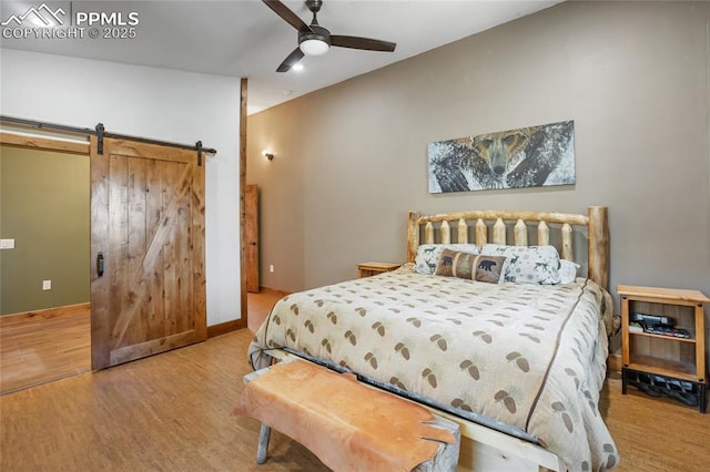 2747 County Road 61, Cripple Creek, CO 80813 - bedroom with wood finished floors, a barn door, a ceiling fan, and baseboards