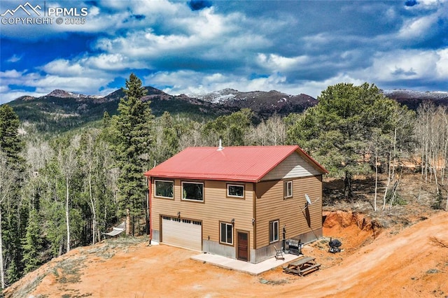2747 County Road 61, Cripple Creek, CO 80813 - view of home's exterior with dirt driveway, a mountain view, a wooded view, and a garage