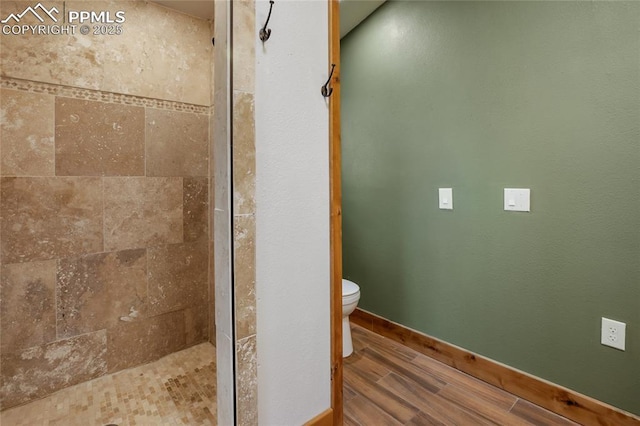 2747 County Road 61, Cripple Creek, CO 80813 - bathroom with wood finished floors, toilet, a tile shower, and baseboards