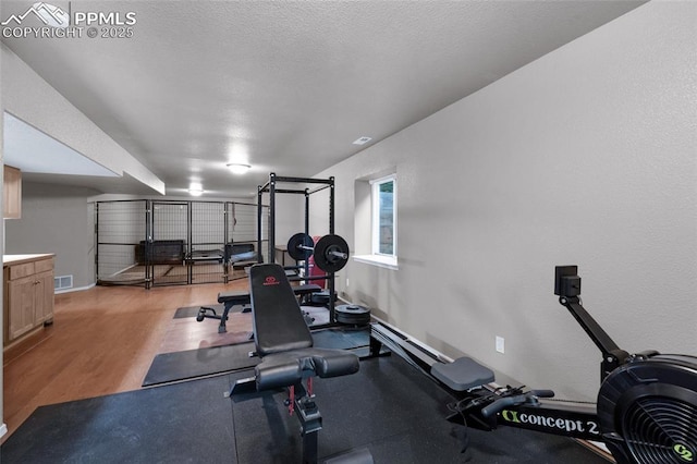 workout room with light wood-type flooring, a garage, and baseboards
