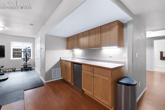 kitchen featuring a textured ceiling, a sink, fridge, baseboards, and dark wood finished floors