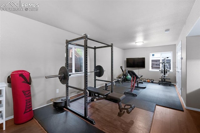 workout area featuring wood finished floors, baseboards, and a textured ceiling