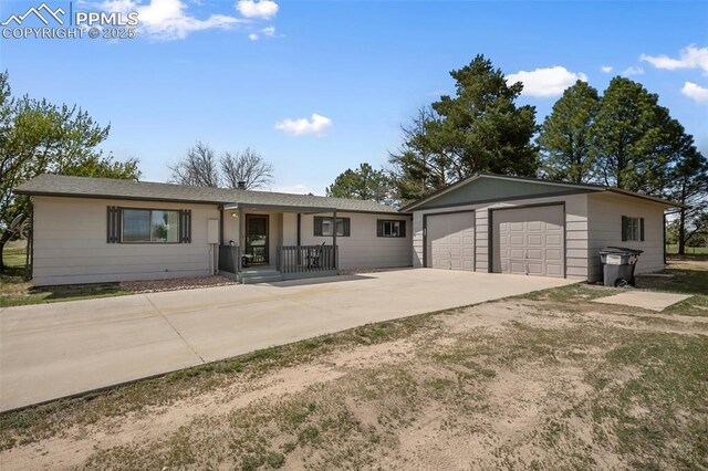 ranch-style home with a porch, driveway, an outbuilding, and an attached garage