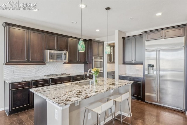 3197 Cool Meadow Pl, Castle Rock, CO 80104 - kitchen with appliances with stainless steel finishes, a sink, dark brown cabinets, dark wood finished floors, and light stone counters